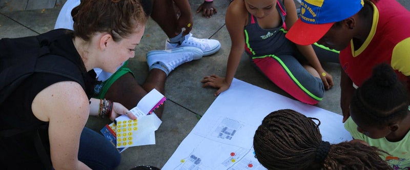 Image of a teacher and students looking at a map on the ground