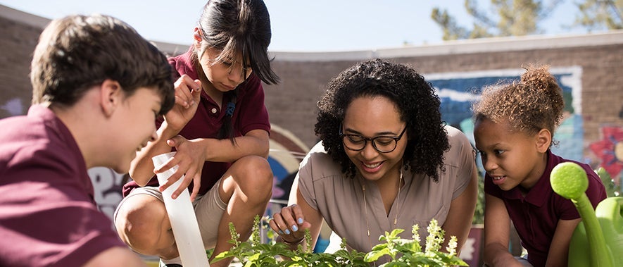 Image of a teacher with students looking at plants in a garden