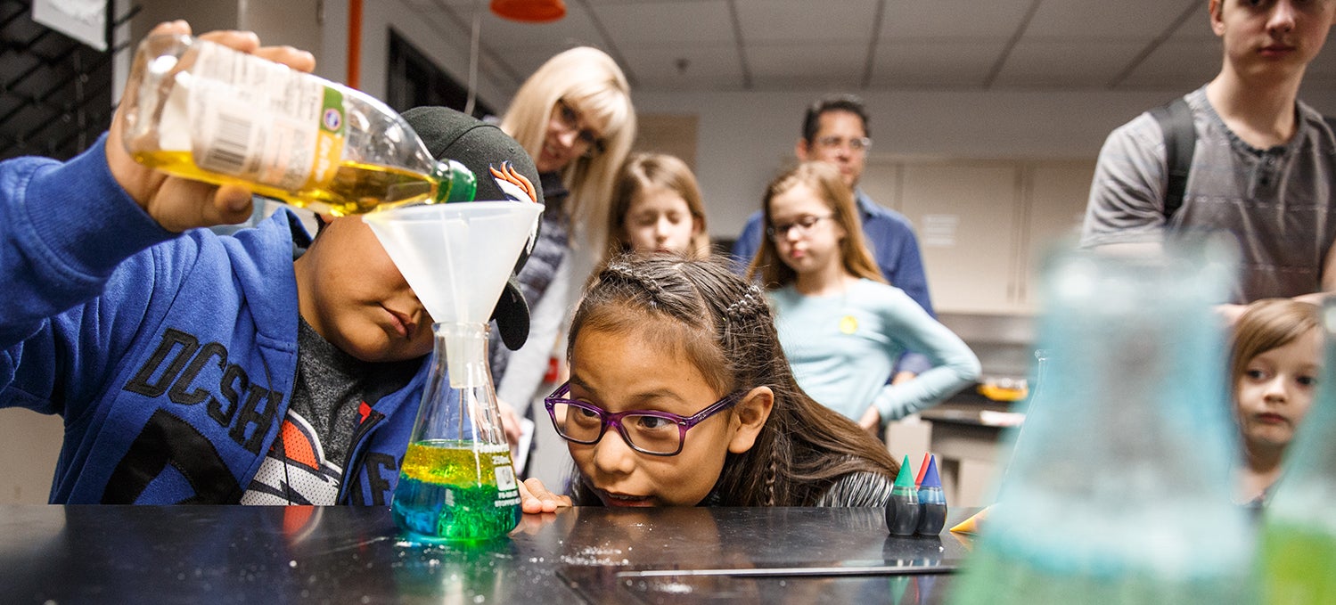 Image of several students observing a flask while mixing liquids