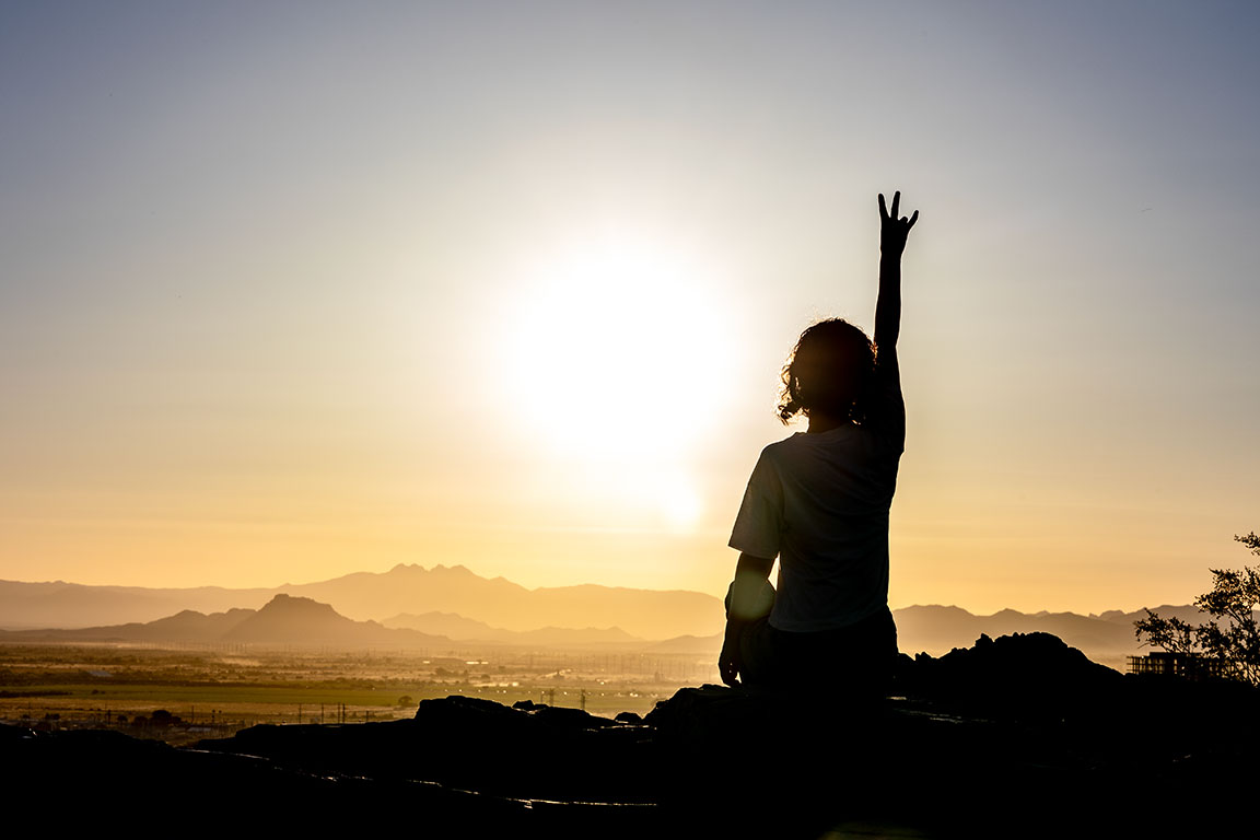 student showing hand sign pitchfork in front of asu phoenix skyline