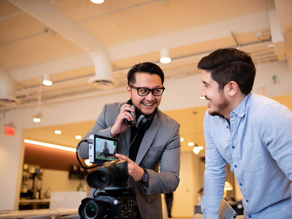 two people reviewing video footage on a screen on location