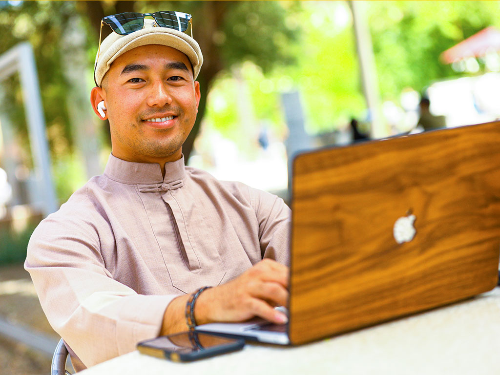  student sitting outside with laptop