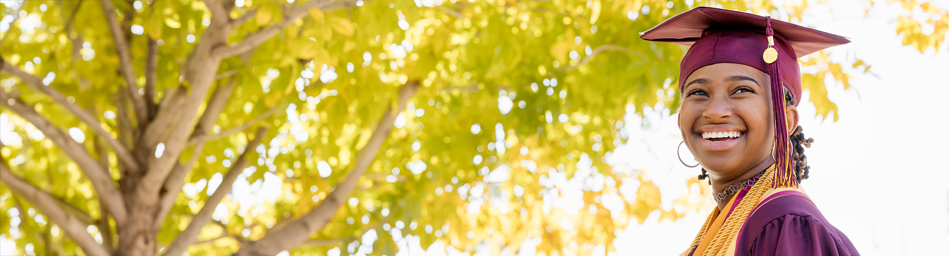 ASU graduate student near trees with gold leaves